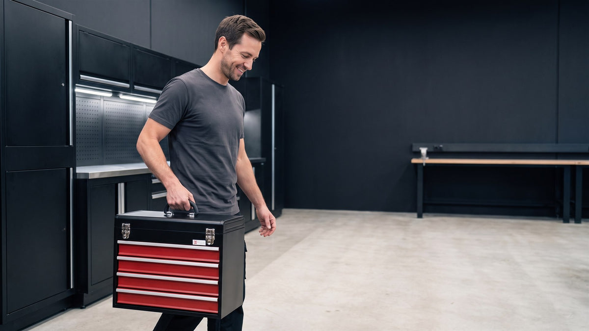 Un bricoleur emporte sa boite a outils metallique noire a tiroirs rouges