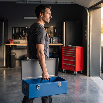 Un bricoleur porte sa caisse a outils bleue par la poignee